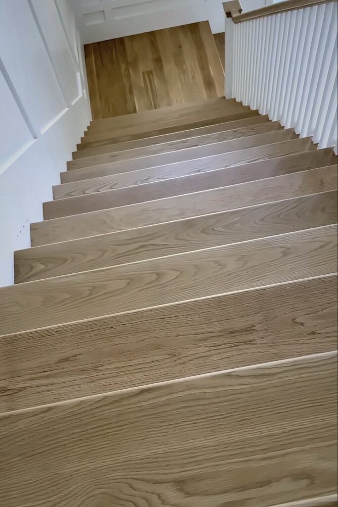 View down a staircase with wood treads and white balusters