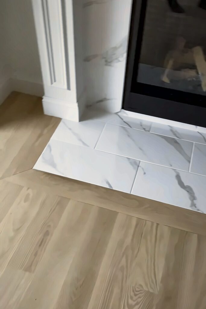 Close-up of wood flooring with a border framing a tiled fireplace hearth