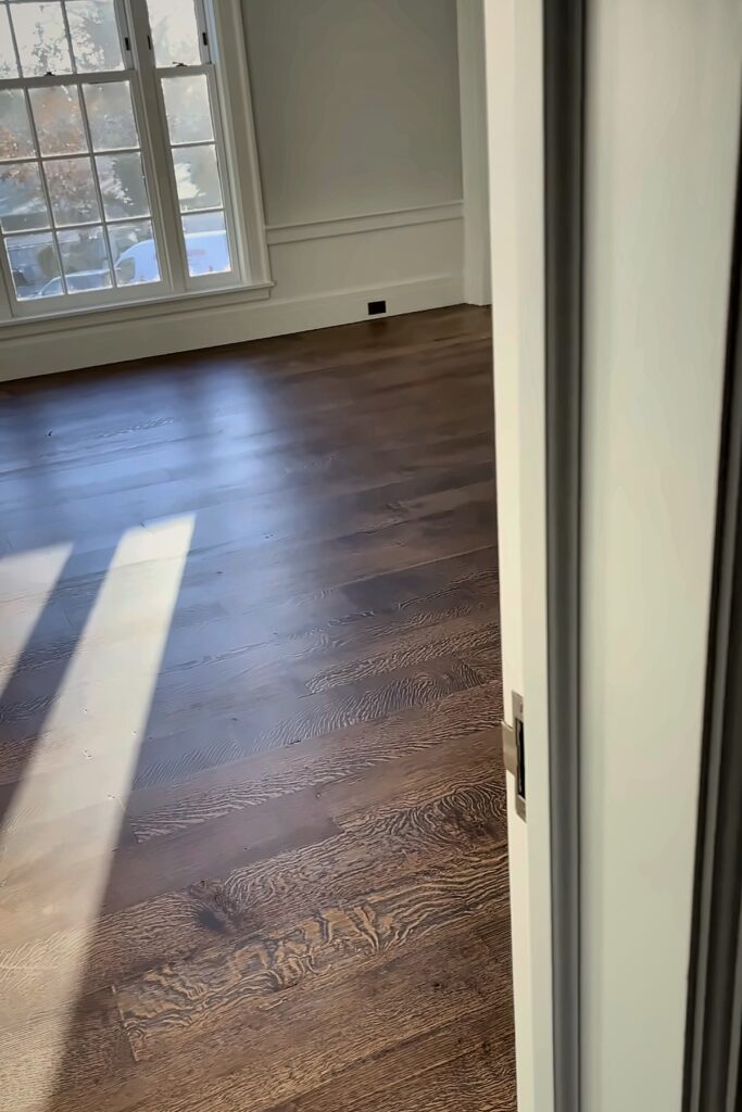Dark wood flooring in an empty room with sunlight from a window