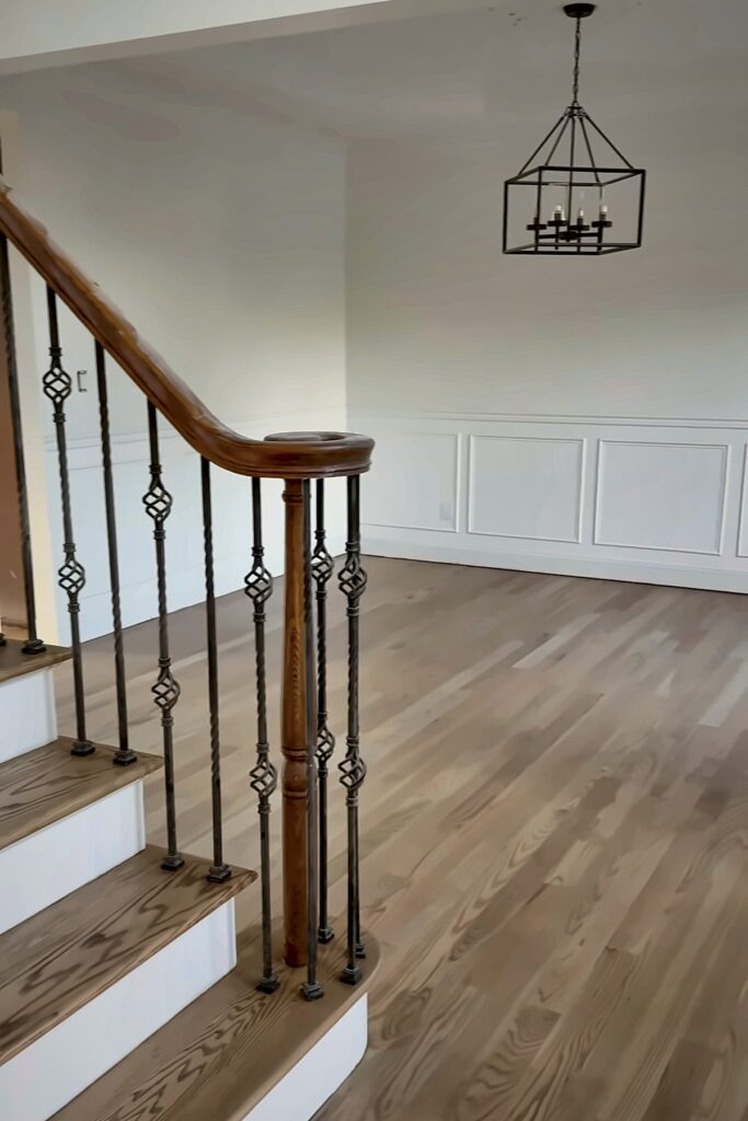 Wood stair treads with metal balusters leading to a room with wood flooring